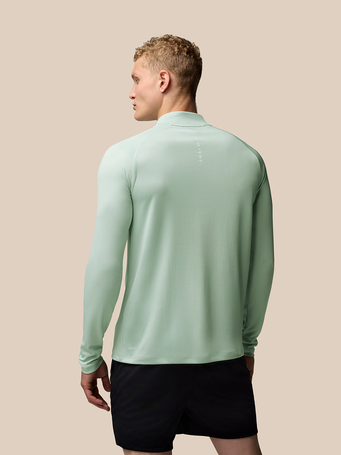 Back view of a man wearing a mint green Adapt Training 1/4 Zip Top with stand collar.