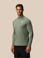 Male model wearing Adapt Training 1/4 Zip Top in Thyme Mint, sage-green long sleeve with chest logo.