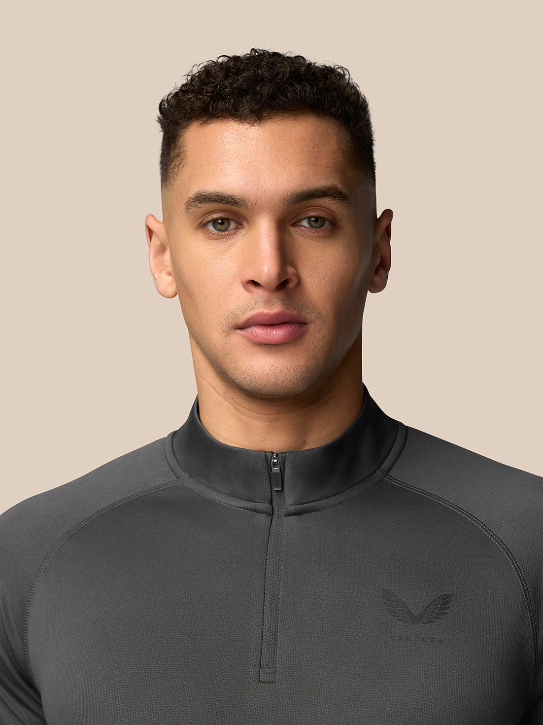 Front view of a man wearing gunmetal Adapt Training 1/4 Zip Top with a center front quarter zip and Castore branding on the left chest