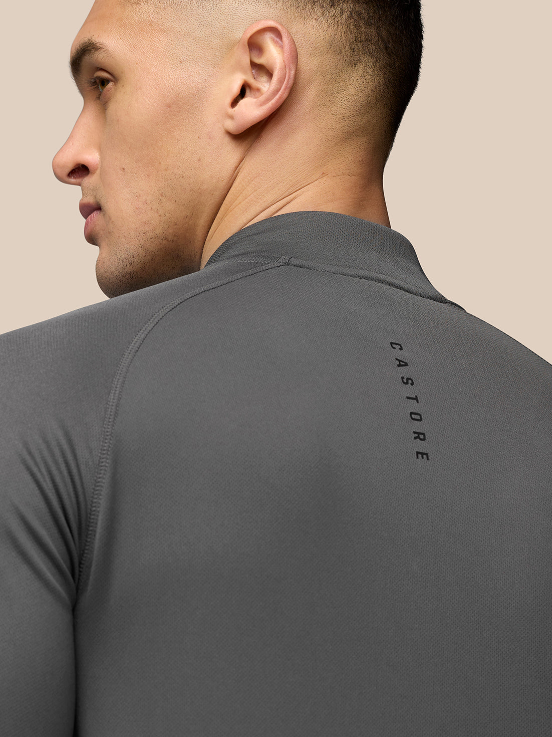 Close-up of gray Adapt Training ¼ Zip top showing textured fabric and Castore branding along the back