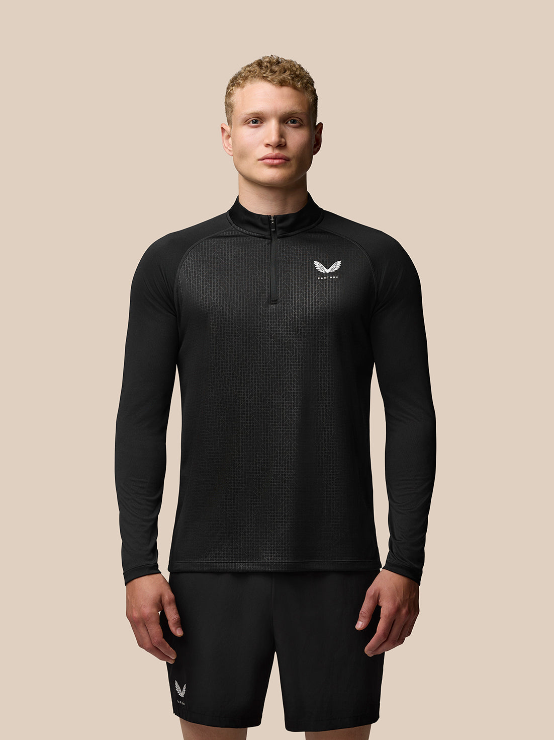 Front view of male model wearing black Adapt Training 1/4 zip top with geometric pattern and Castore logos on chest and upper back.