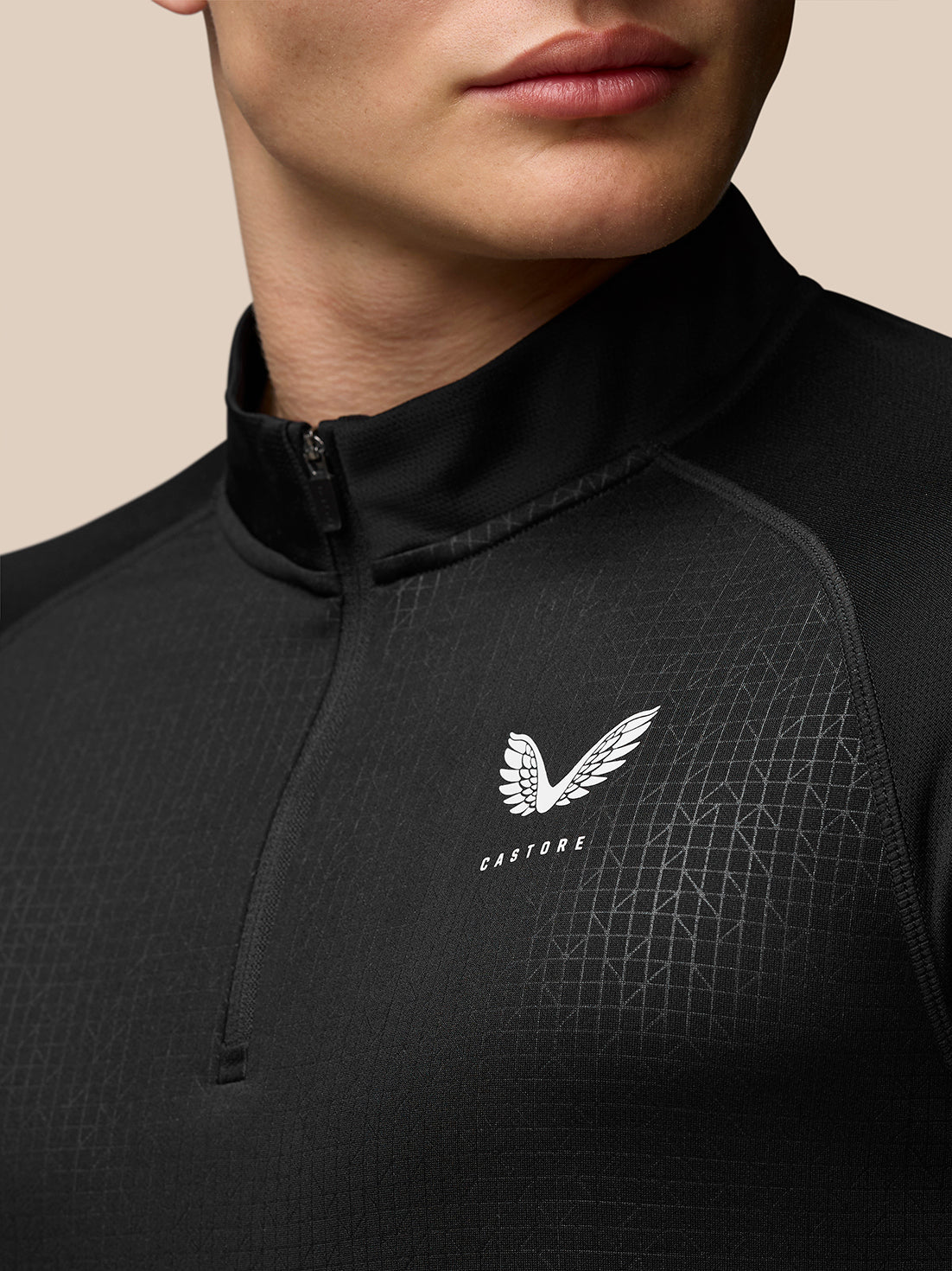 Close up of black Adapt Training 1/4 Zip Top showing stand collar and geometric pattern with Castore logo on chest and Aertek branding at lower back