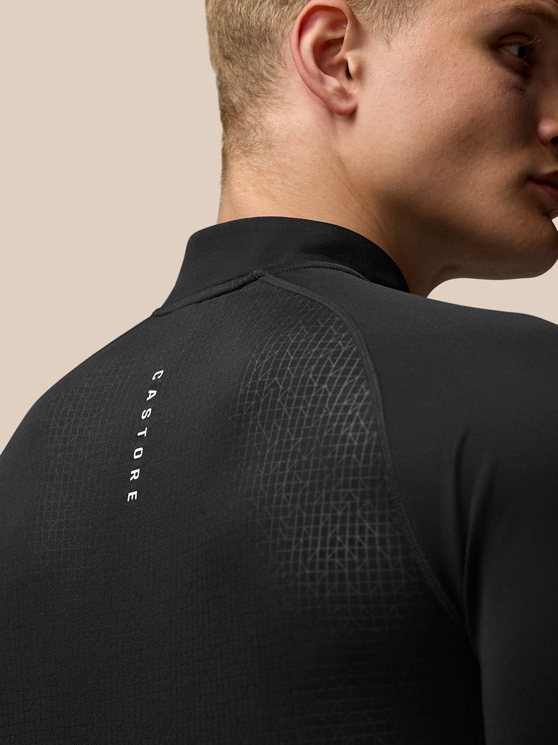 Back view of black Adapt Training Top with geometric pattern and Castore branding on upper back, Aertek branding at lower back
