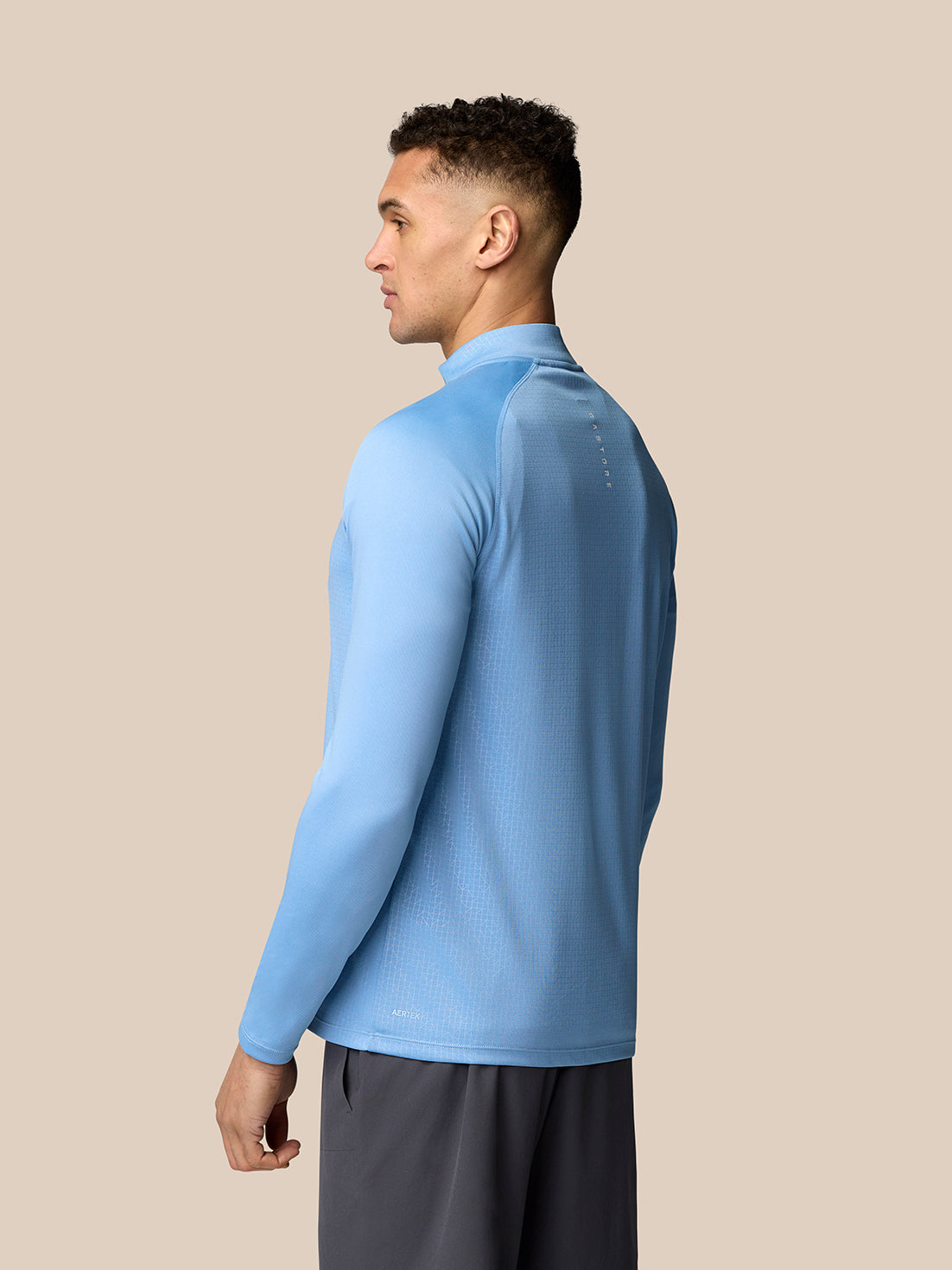 Back view of sky blue Adapt Training 1/4 Zip Top on a model showing branding along the upper back.