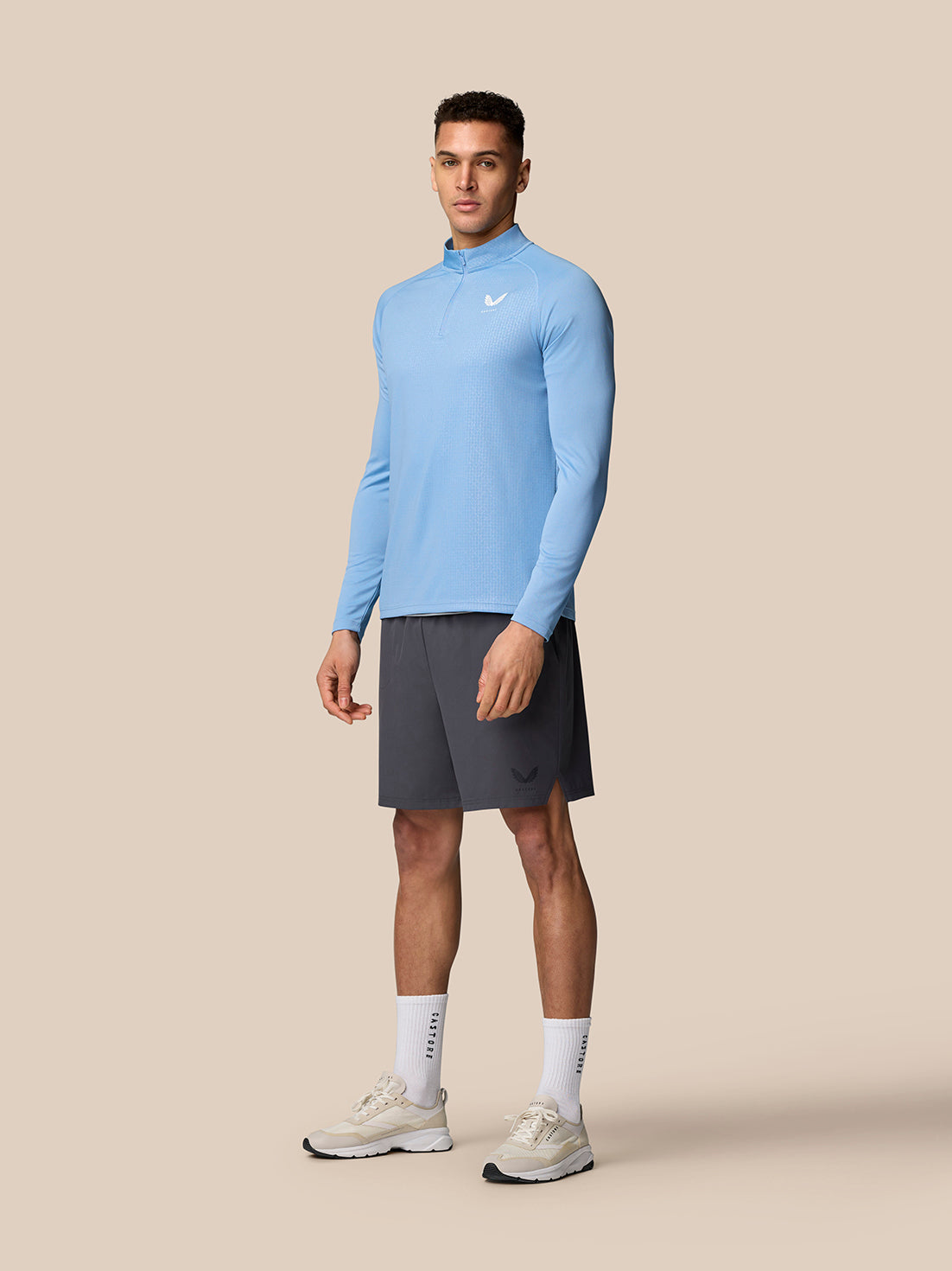 Male model wearing sky blue Adapt Training 1/4 Zip top with raglan sleeves and Castore logos