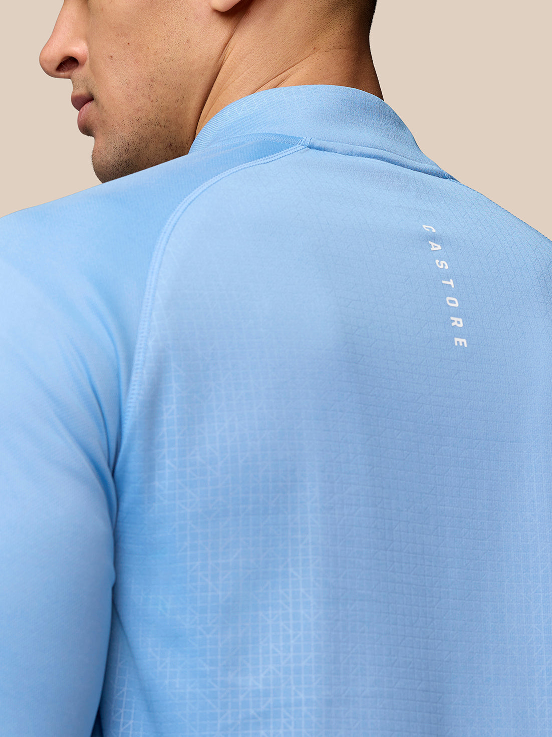 Back view of sky blue Adapt Training 1/4 Zip Top showing vertical Castore branding along the upper back and a subtle pattern.