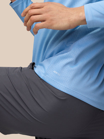 Close up of the lower back hem of sky blue Adapt Training 1/4 Zip Top with AERTEK branding.