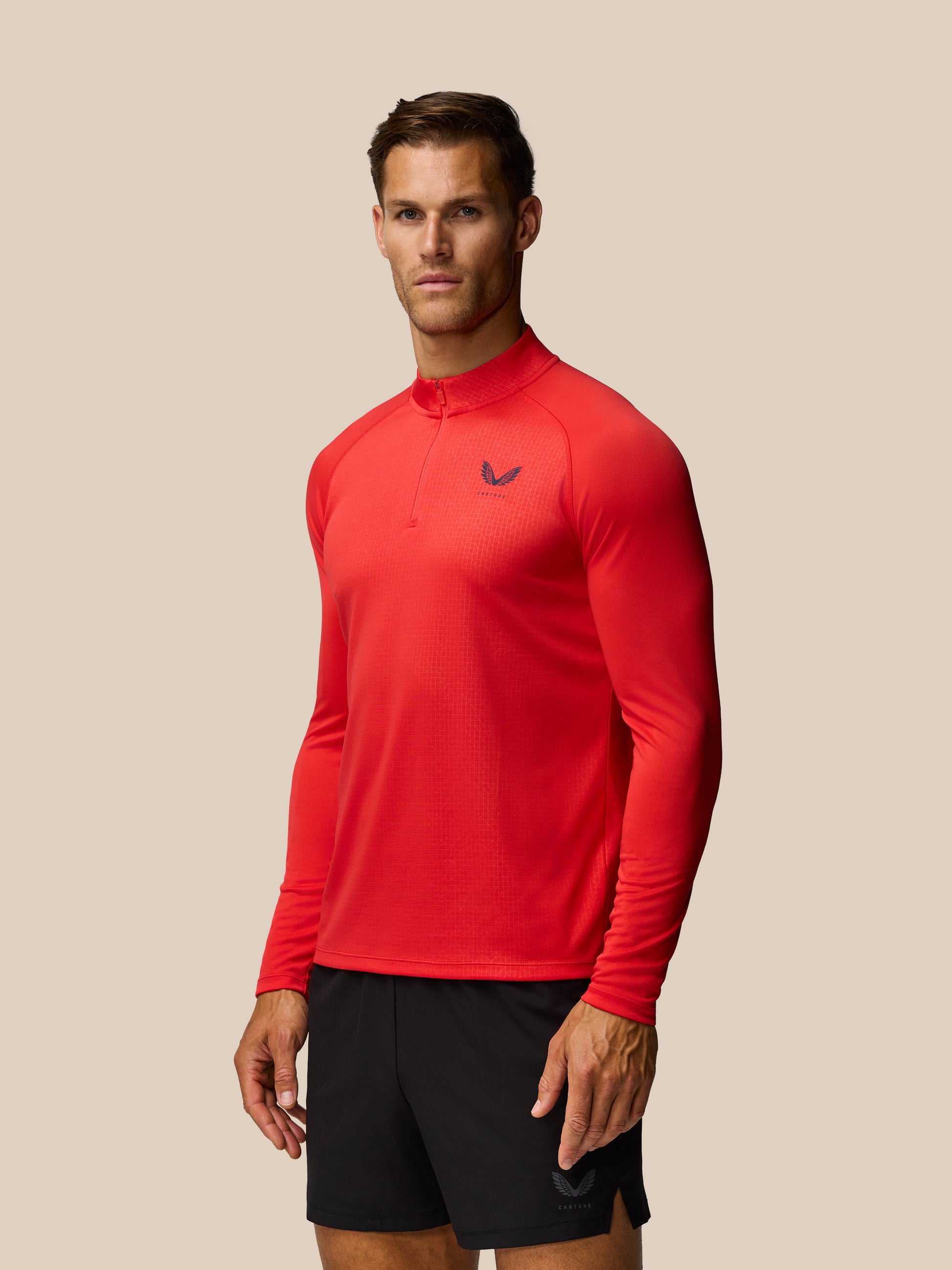 Red Adapt Training raglan long sleeve quarter-zip top with Castore logo on left chest against a beige backdrop