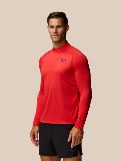 Red Adapt Training raglan long sleeve quarter-zip top with Castore logo on left chest against a beige backdrop