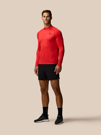 Side view of a man wearing red Adapt Training quarter-zip top with left chest logo and black shorts