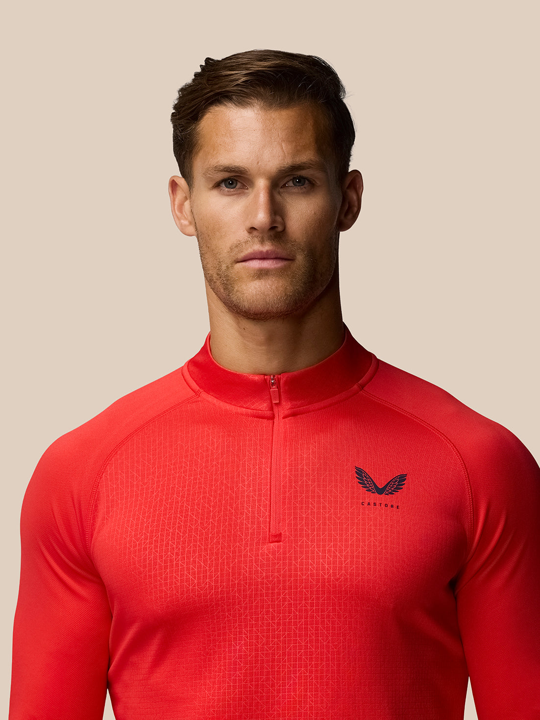 Front view of a man in red Adapt Training raglan long sleeve quarter-zip top with Castore logo on the left chest