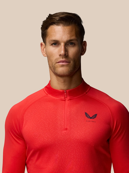 Front view of a man in red Adapt Training raglan long sleeve quarter-zip top with Castore logo on the left chest