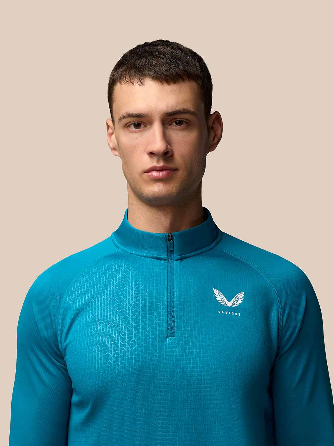 Front view of model wearing Dark Aqua Men’s Adapt Print 1/4 Zip Top with geometric pattern and Castore logo on left chest