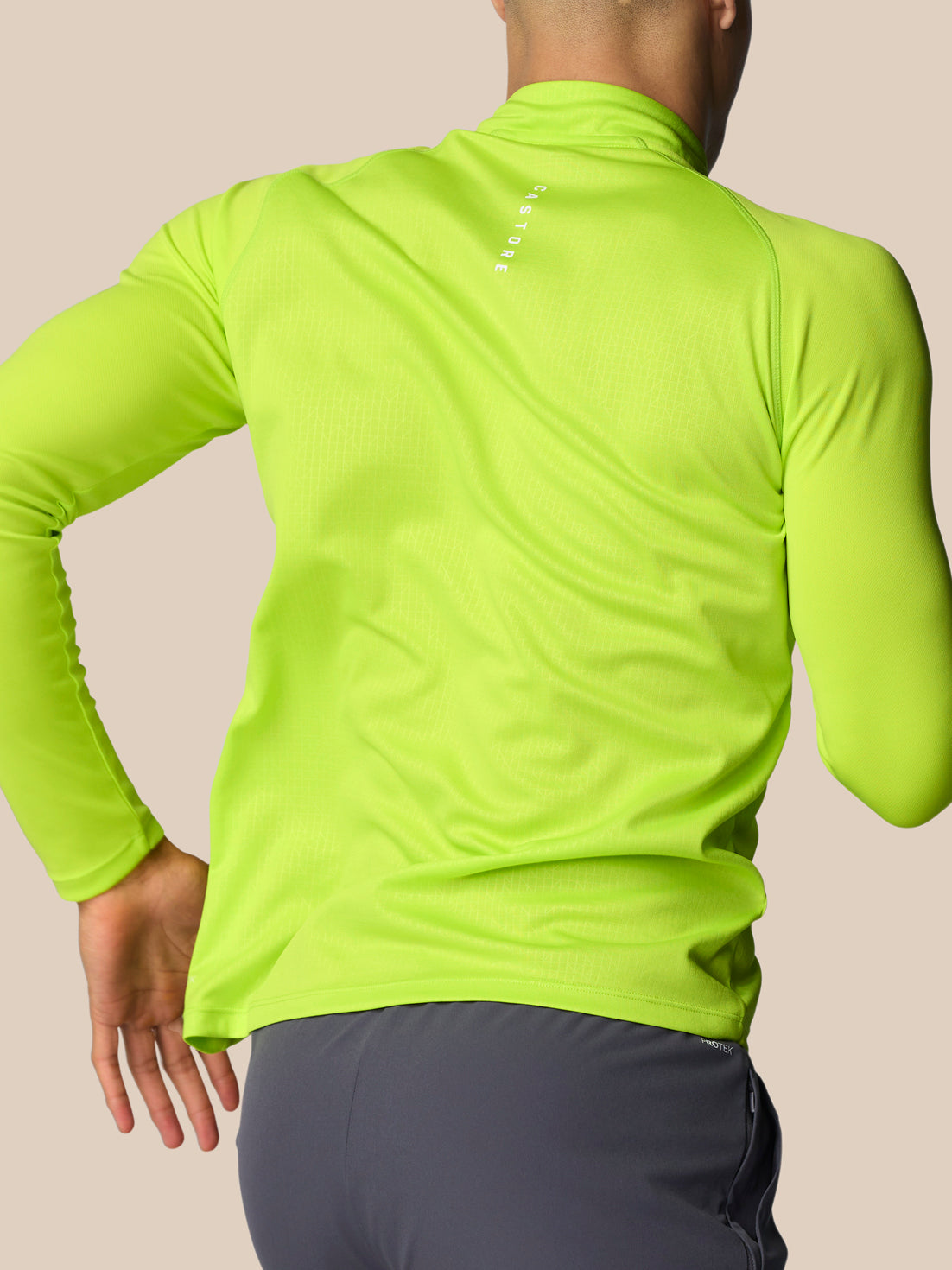 Back view of lime green Adapt Training quarter zip top with CASTORE branding on the upper back