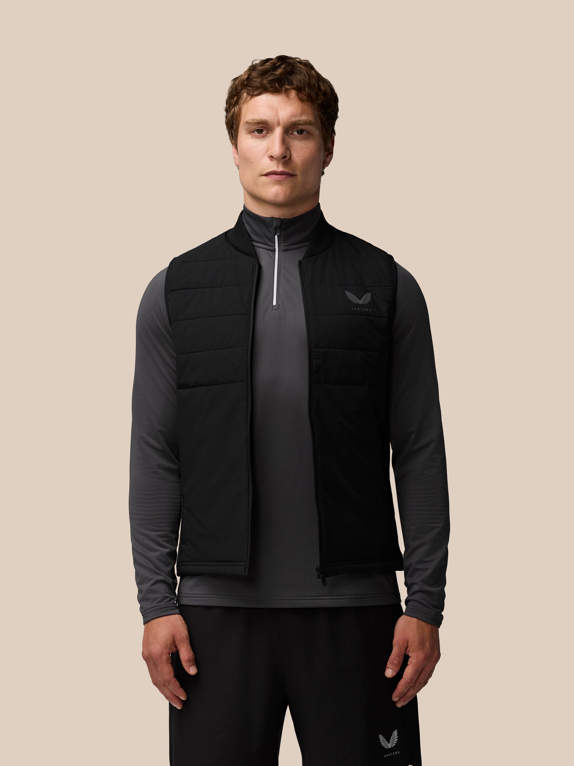 Back view of a man in a black Apex Training Gilet showing vertical Castore branding along the center back.