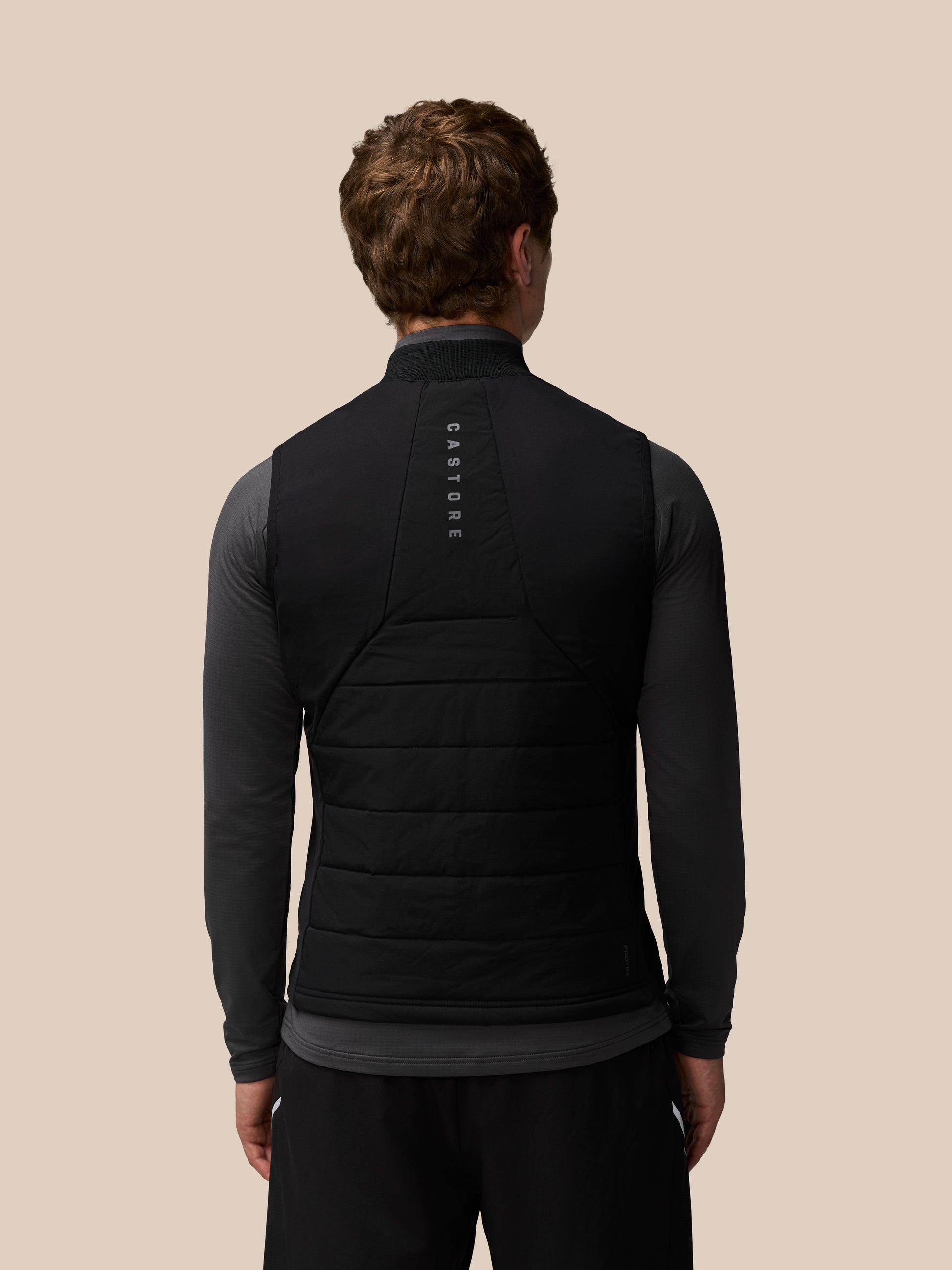 Rear view of a black sleeveless gilet with Castore branding along the back panel.