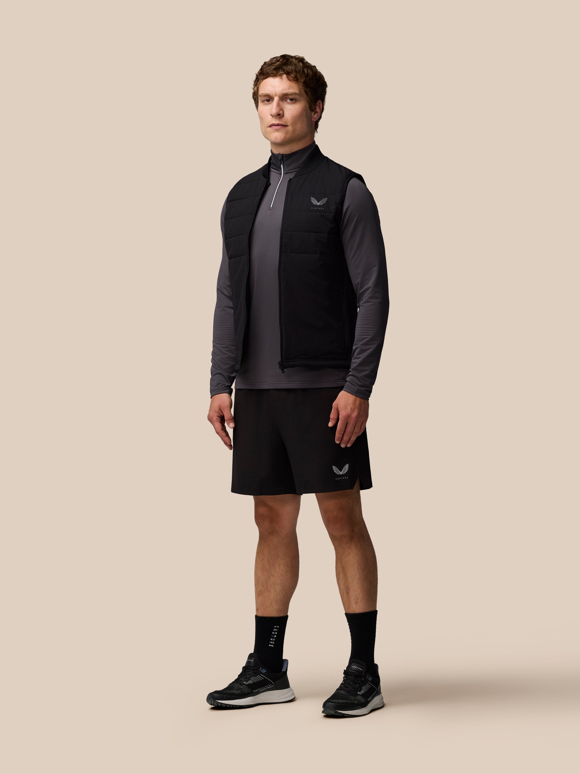 Male model wearing black Apex Training Gilet sleeveless puffer vest with stand collar