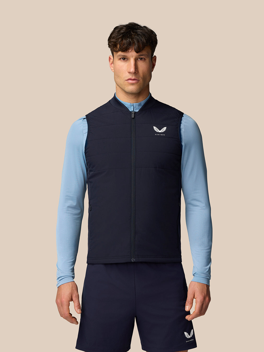 Male model wearing a navy Apex Training Gilet over a light blue long sleeve shirt.
