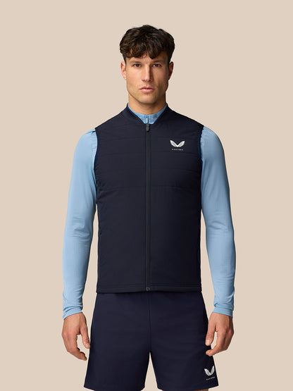 Male model wearing a navy Apex Training Gilet over a light blue long sleeve shirt.