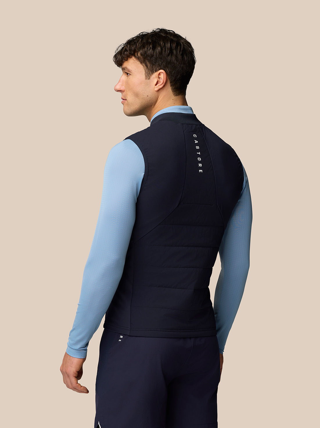 Back view of navy Apex Training Gilet showing vertical Castore branding on the upper back