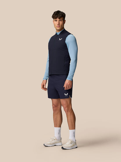 Male model wearing navy Apex Training Gilet over a light blue top and navy shorts with Castore logo on the chest