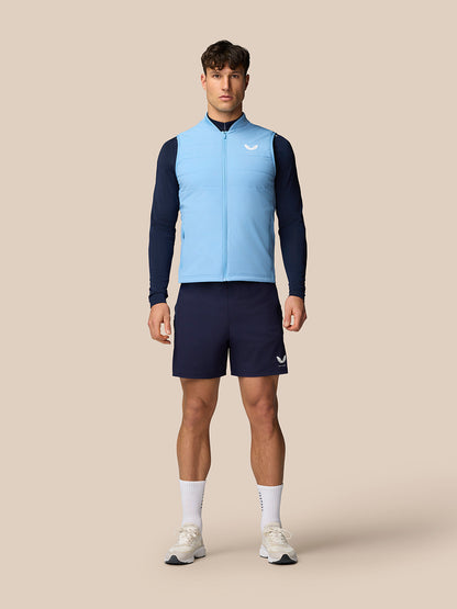 Male model wearing sky blue Apex Training Gilet over navy base layer in a full body shot