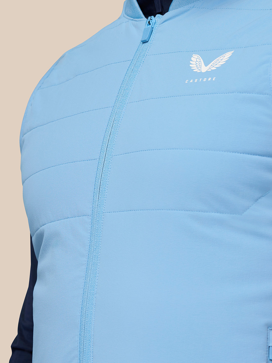 Front close-up of sky blue Apex Training Gilet chest area showing zipper and Castore logo.