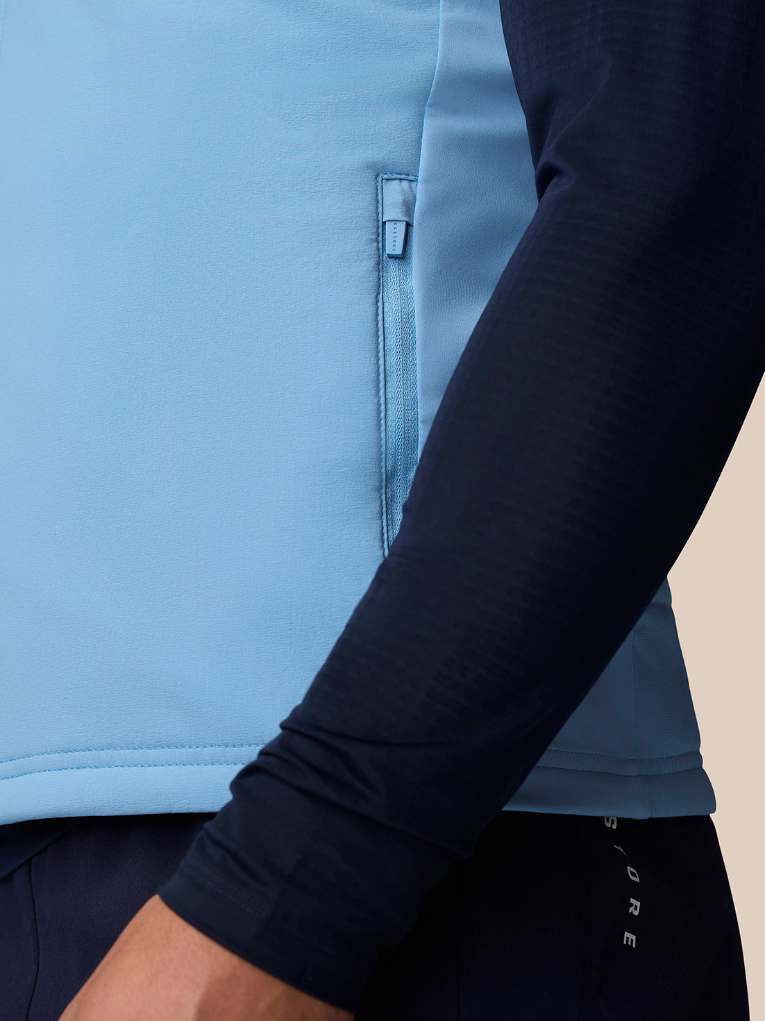 Close up of the sky blue gilet showing side zip pocket and seam details on the fabric