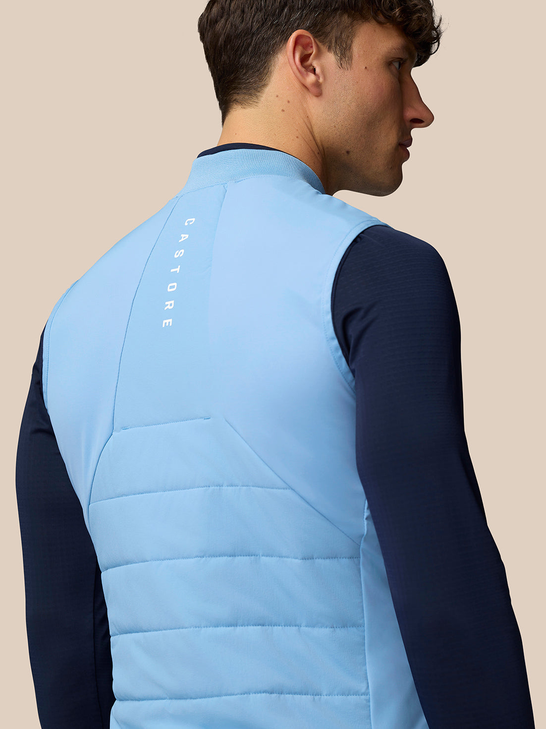 Back view of a sky blue Apex Training Gilet on a model with vertical Castore branding along the back.