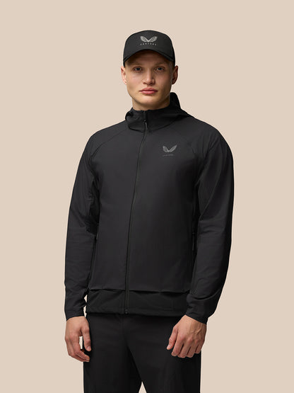 Male model wearing black Flex Hooded Jacket with hood down and cap, full-body portrait