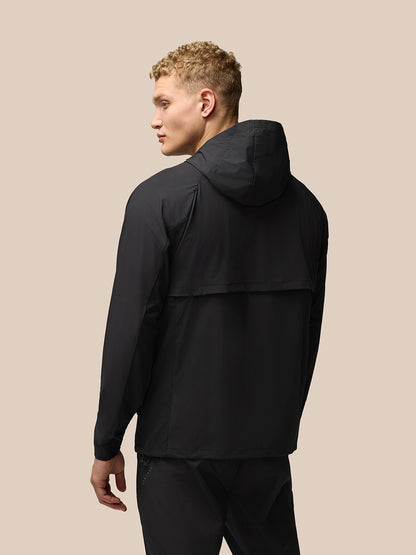Rear view of a man in a black Flex Hooded Jacket with hood down and streamlined silhouette.