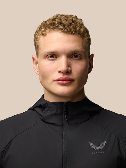 Back view of a man wearing a black Flex Hooded Jacket highlighting clean lines and lightweight fabric.