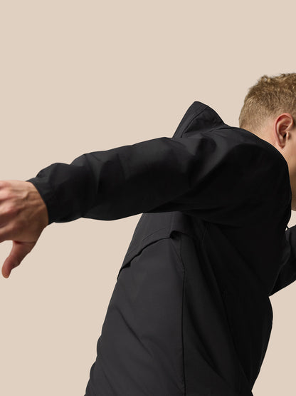 Close-up of black Flex Hooded Jacket showing sleeve and hood against a beige backdrop
