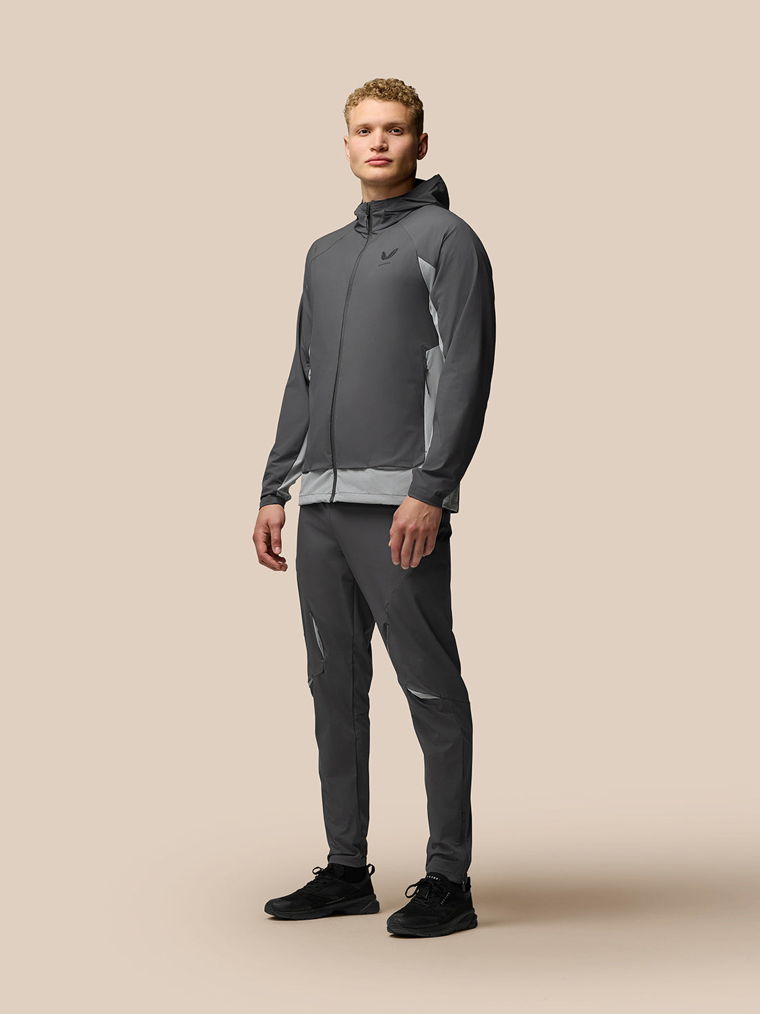 Male model wearing grey Flex Hooded Jacket with front zip and light side panels; Castore branding on chest