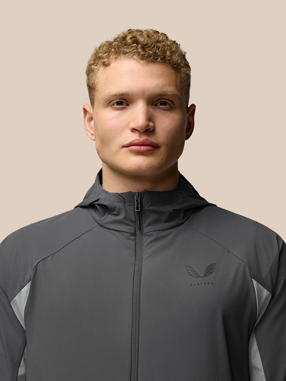 Male model wearing grey Flex Hooded Jacket with full front zip hood down and Castore logo on chest.