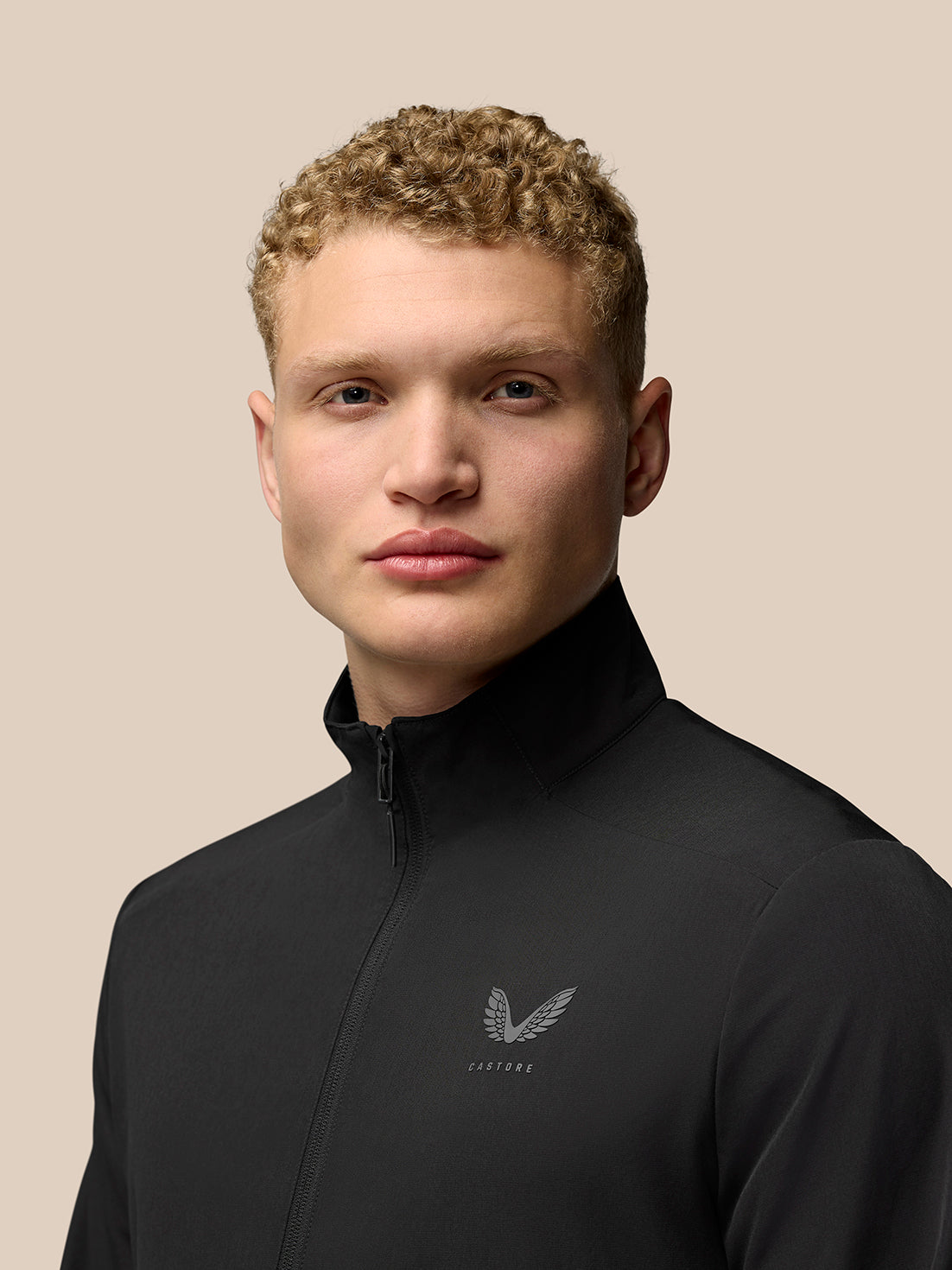 Close up of model wearing black Flex Cargo Jacket with zip front and Castore logo on the chest