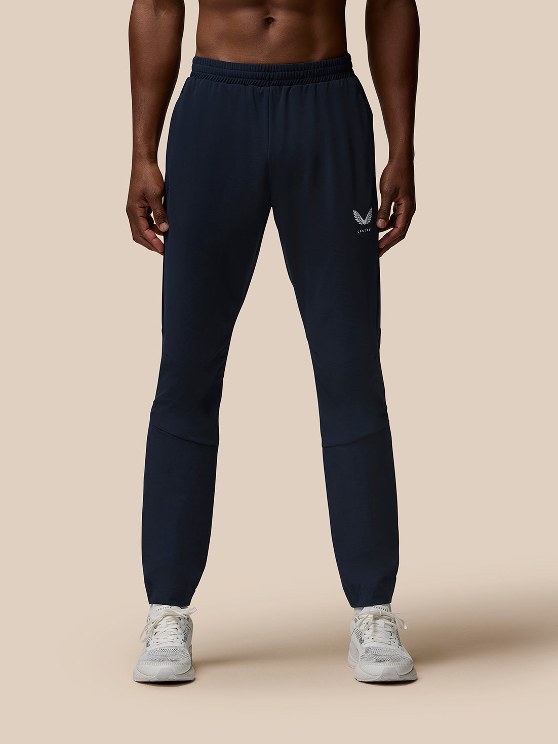 Front view of male model in navy Flow Training Joggers with zipped pockets and Castore branding on thigh and calf
