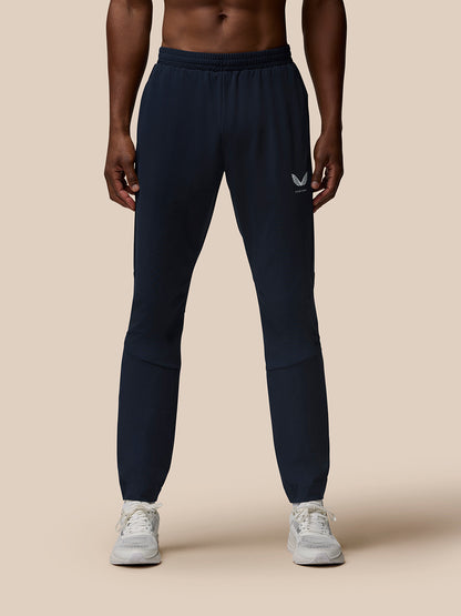 Front view of male model in navy Flow Training Joggers with zipped pockets and Castore branding on thigh and calf