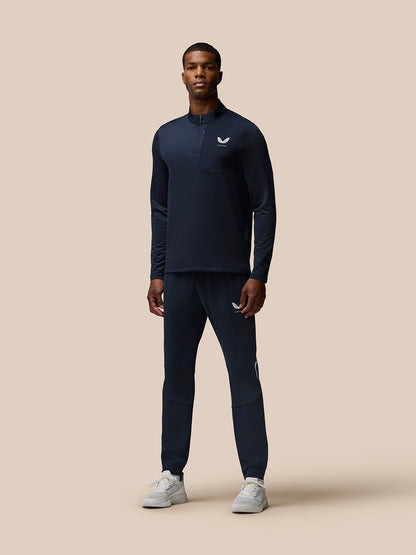 Male model in navy training set with quarter zip top and matching Flow Training Joggers with Castore logos on chest and thigh