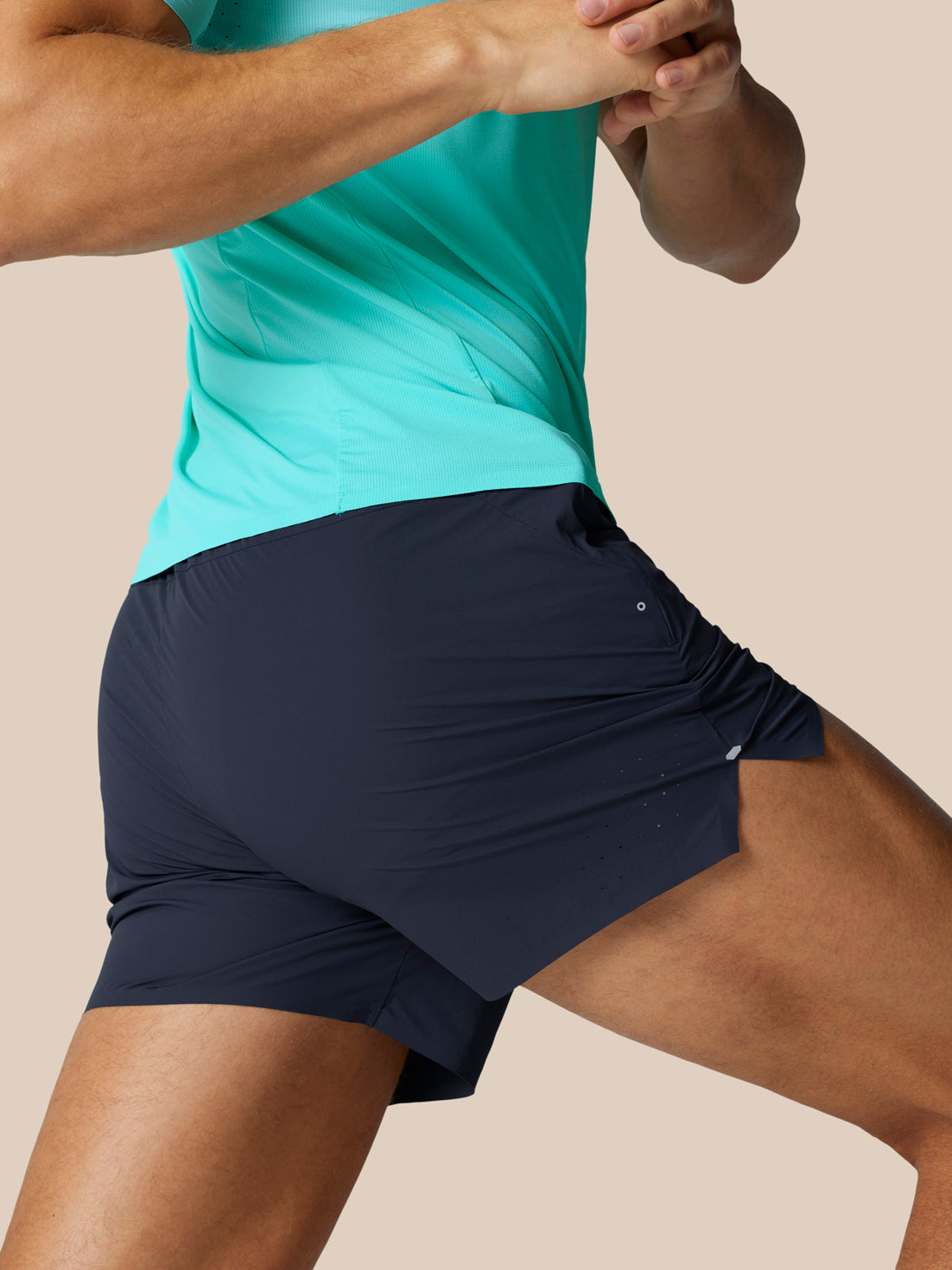 Side view of a runner wearing navy Zone Training Shorts with teal top.