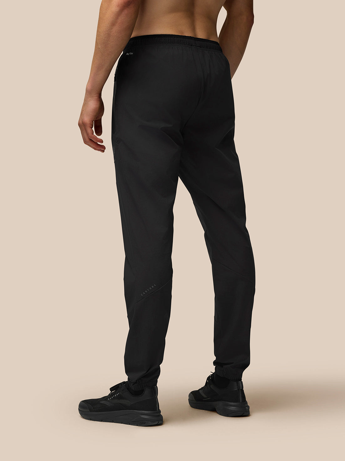 Back view of a model wearing black Flex Lightweight Joggers with an elastic waistband and Castore branding on the left leg