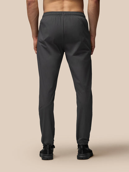 Back view of a man wearing dark grey lightweight flex joggers with an elastic waistband and left leg branding.