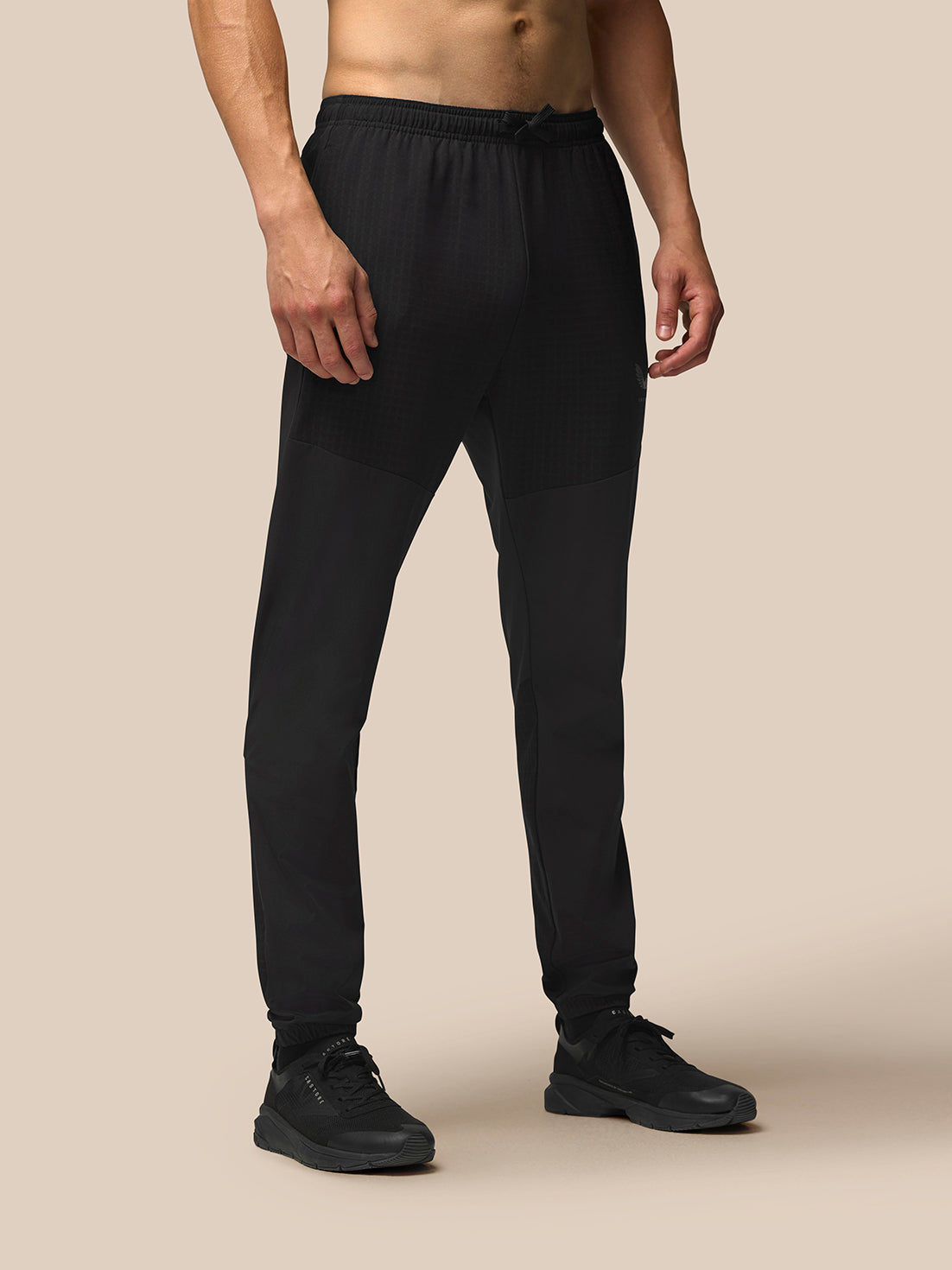 Front view of a man wearing black Winterised Flex Joggers with a drawcord waistband and zip pockets.