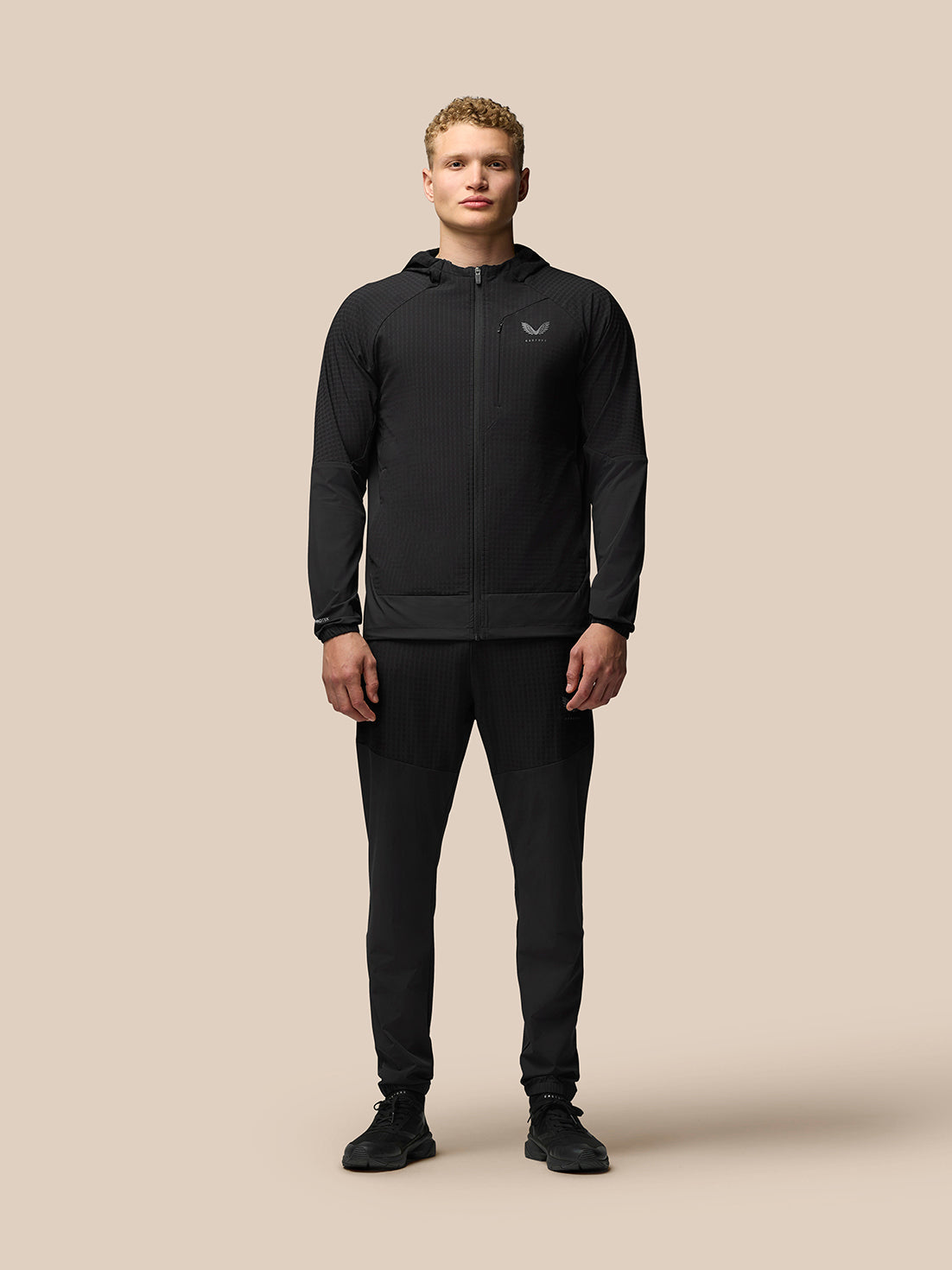 Male model wearing black Winterised Flex Joggers with elastic cuffs and a matching jacket