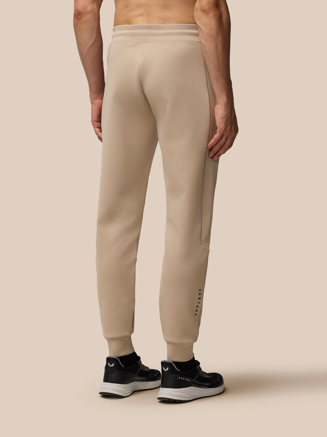 Back view of a man wearing Mushroom Flex Lifestyle Joggers showing the elastic waistband and logos on the leg