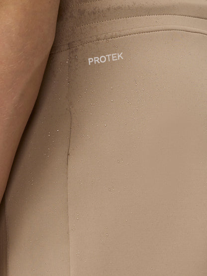 Close up of beige jogger fabric with ProTek logo and water droplets highlighting water resistance