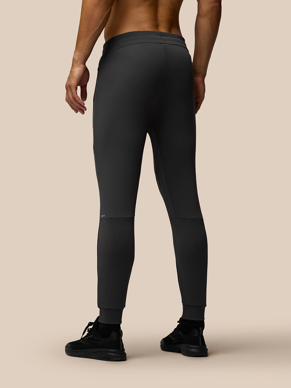 Back view of model in charcoal Flex Thermo Joggers with tapered cuffs and waistband