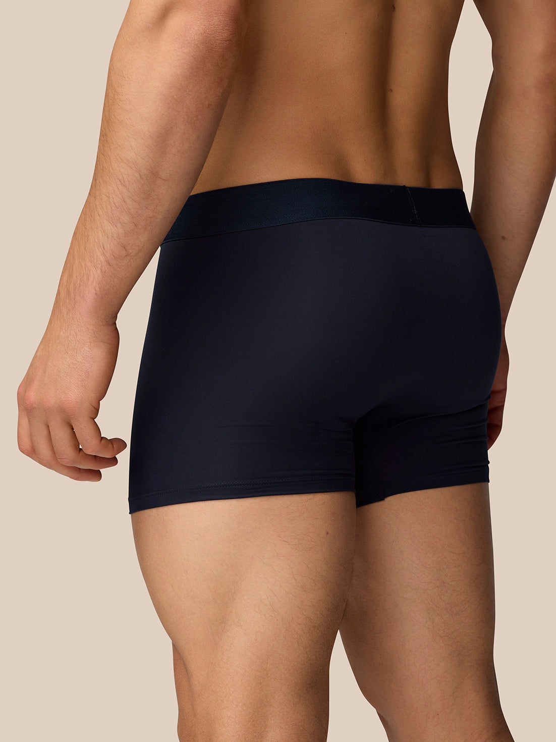 Rear view of a man in navy boxer shorts with contoured seams and snug fit
