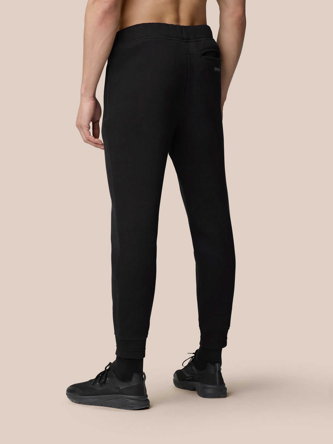 Back view of a person wearing black Adapt Fleece Joggers with cuffed hems