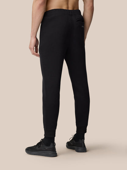 Back view of a person wearing black Adapt Fleece Joggers with cuffed hems